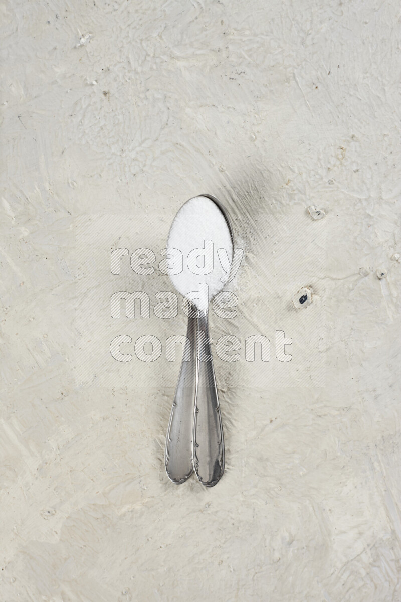 2 metal spoons filled with fine table salt and fine pink himalayan salt on white background