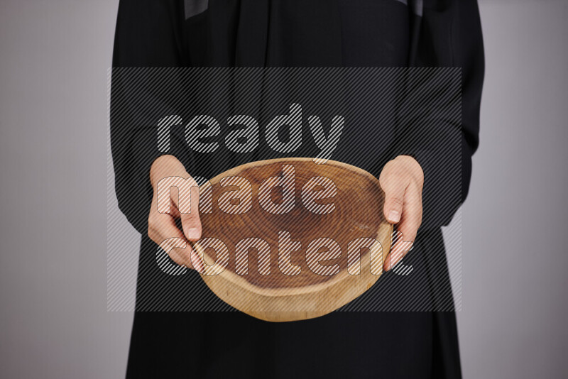 A woman in black abaya holding different wooden essentials in different positions