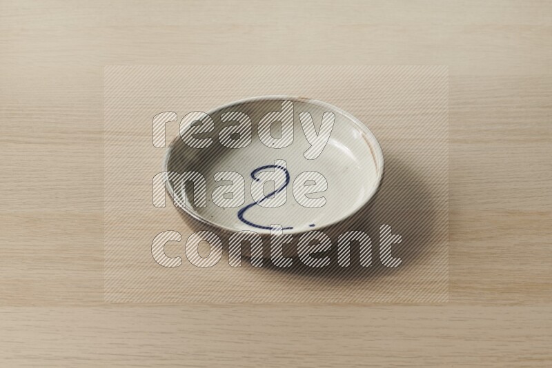 A multicolored pottery bowl on light wooden background