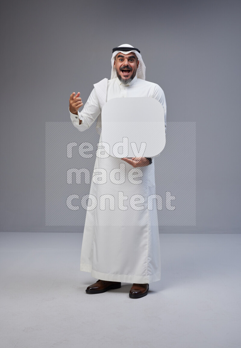 Saudi man Wearing Thob and white Shomag standing holding social media sign on Gray background