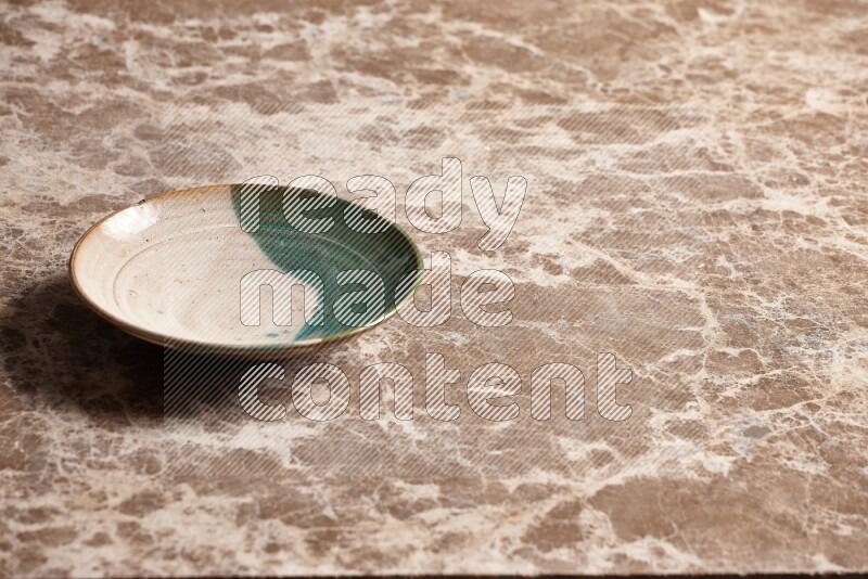 A multicolored pottery plate on beige marble background