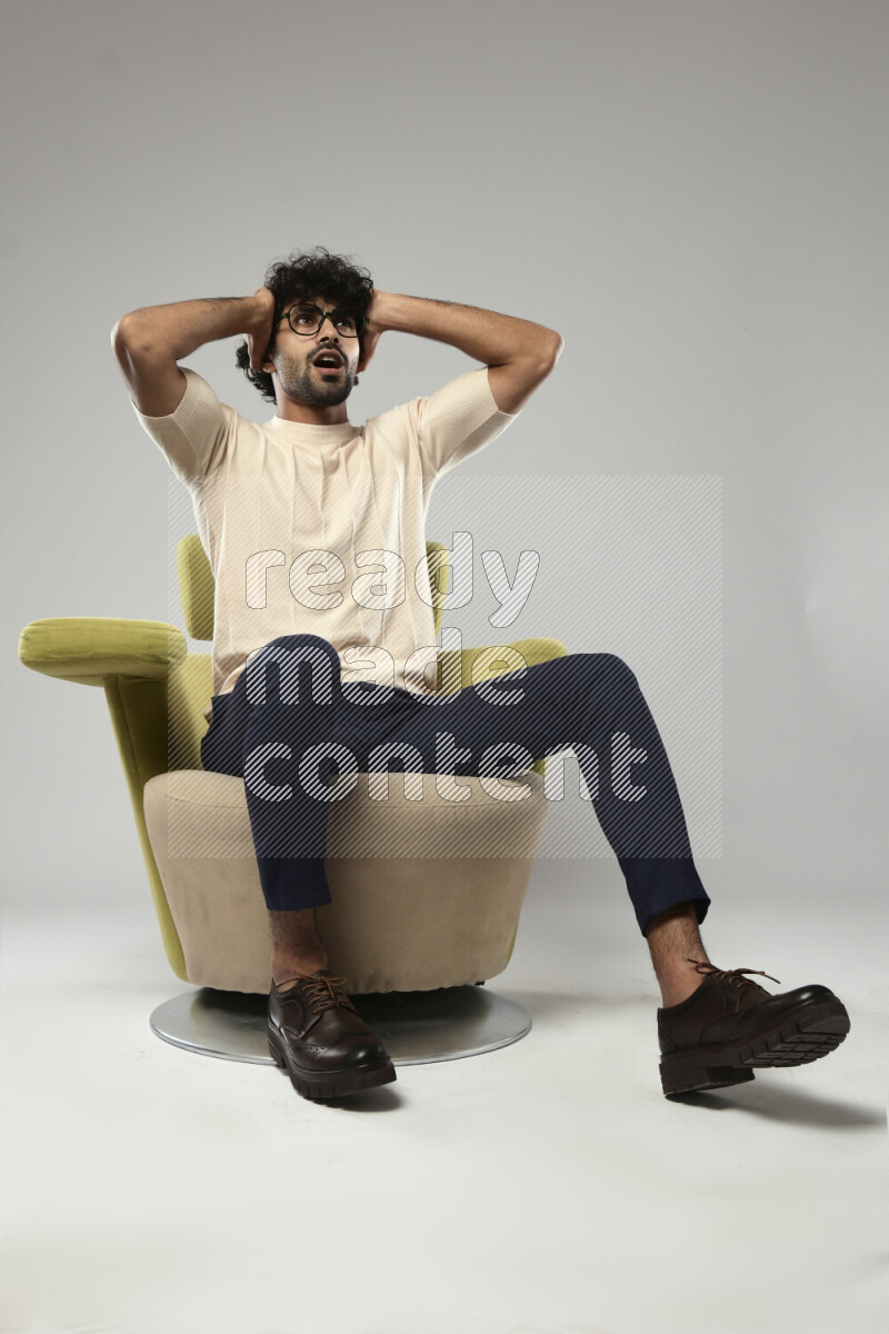 A man wearing casual sitting on a chair making a hand gesture on white background