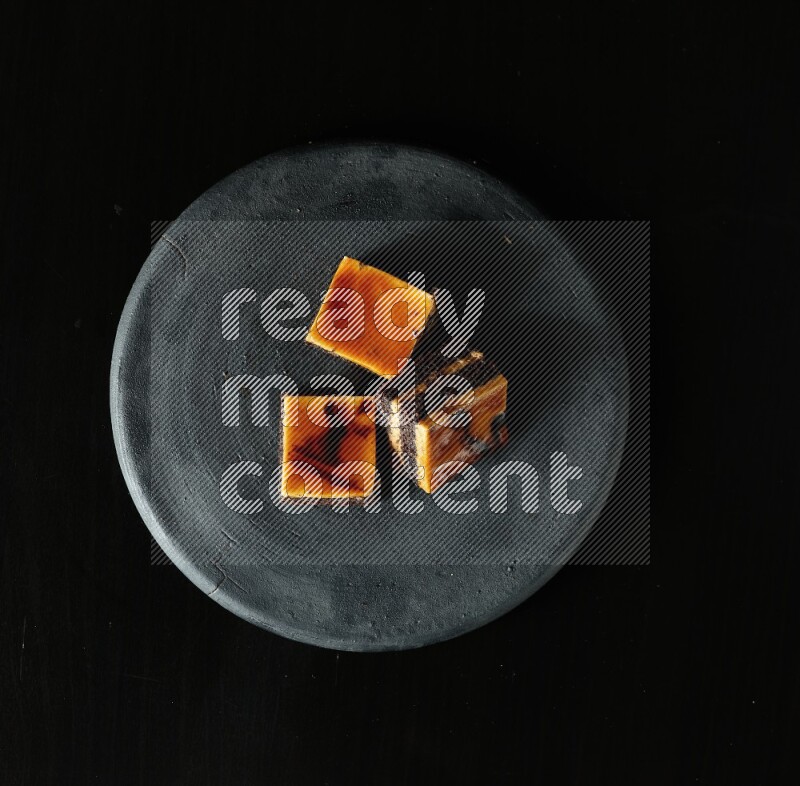 Assorted desserts in a black pottery plate on black background