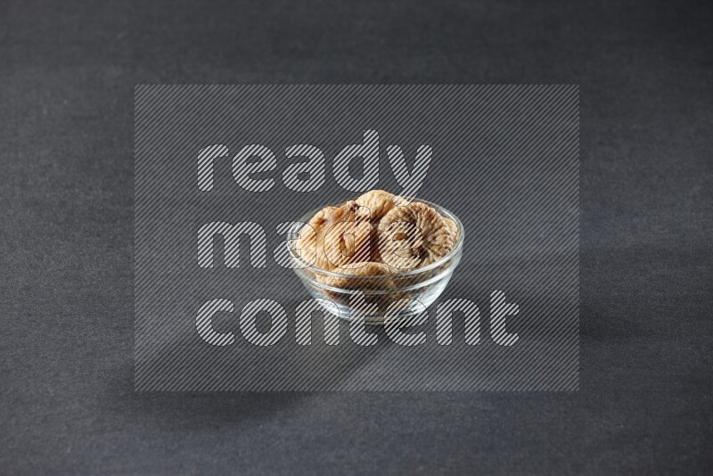 A glass bowl full of dried figs on a black background in different angles