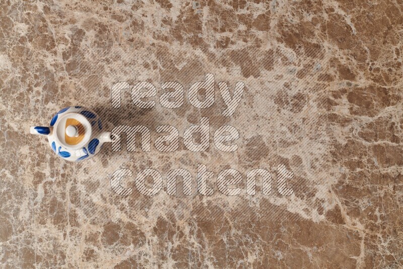 إبريق شاي فخاري على خلفية رخام بيج