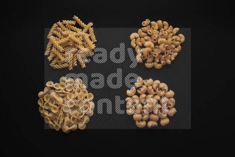 Different pasta types in bunches on black background