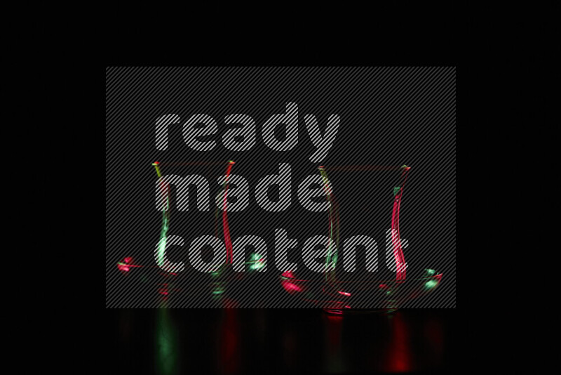 أواني زجاجية مع حواف مضيئة باللونين الأحمر والأخضر على خلفية سوداء