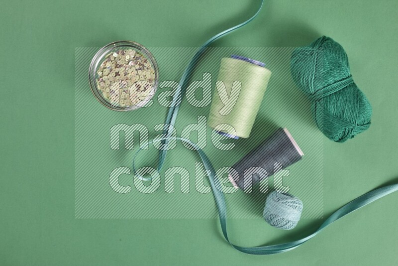 A green collection of sewing and tailoring tools arranged on a green background