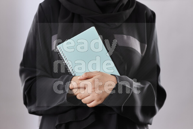A woman in abaya holding books and a board in different positions (back to school)