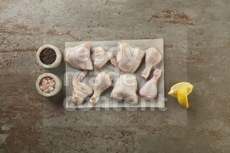 Mixed fresh chicken pieces on a parchment paper direct on a textured rustic background