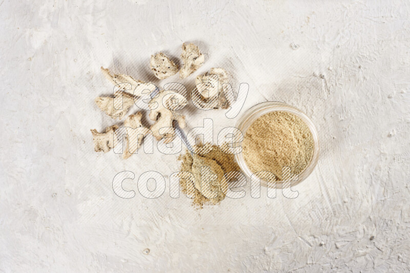 A glass jar full of ground ginger powder on white background