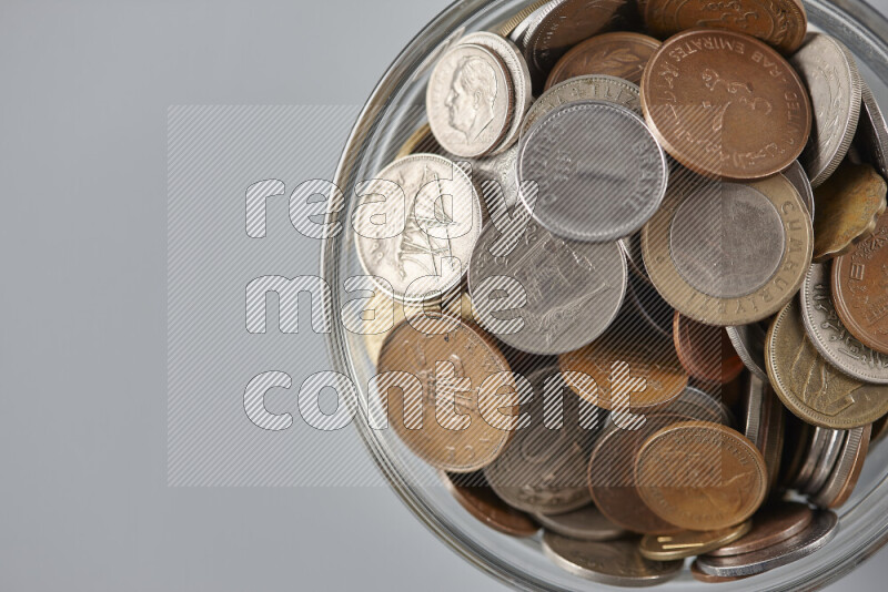 Random old coins in a glass bowl on grey background