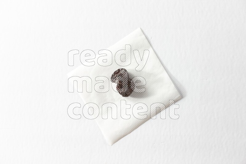 Two dried plums on a piece of paper on a white background in different angles