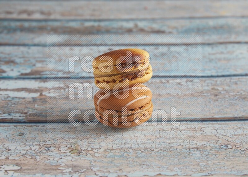 45º Shot of of two assorted Brown Irish Cream, and Yellow Crème Brulée macarons on light blue background