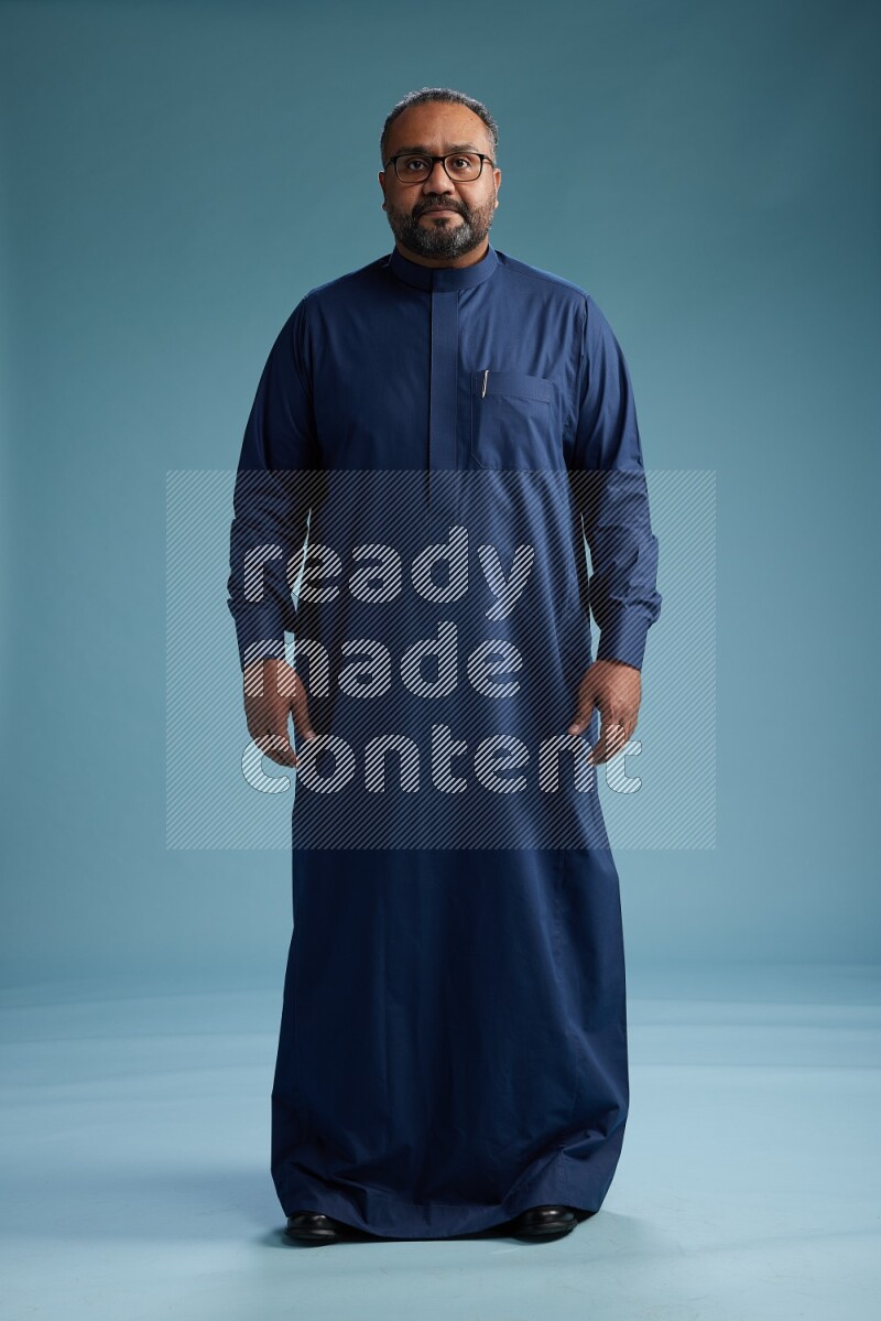 Saudi Man without shimag Standing Interacting with the camera on blue background