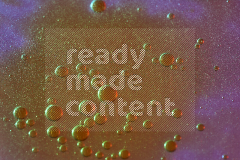 Close-ups of abstract yellow watercolor drops on oil Surface on pink background