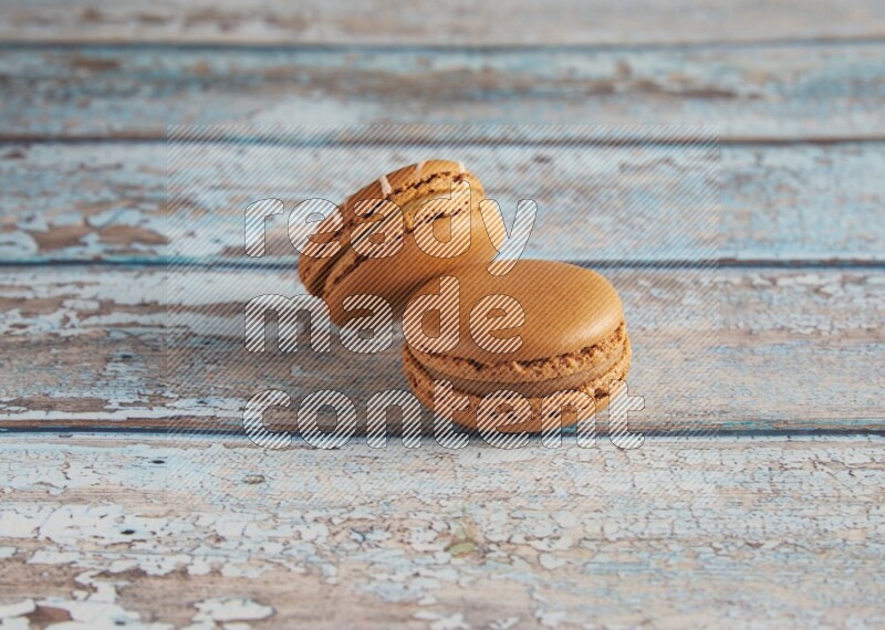 45º Shot of of two assorted Brown Irish Cream, and Brown Maple Taffy macarons  on light blue background