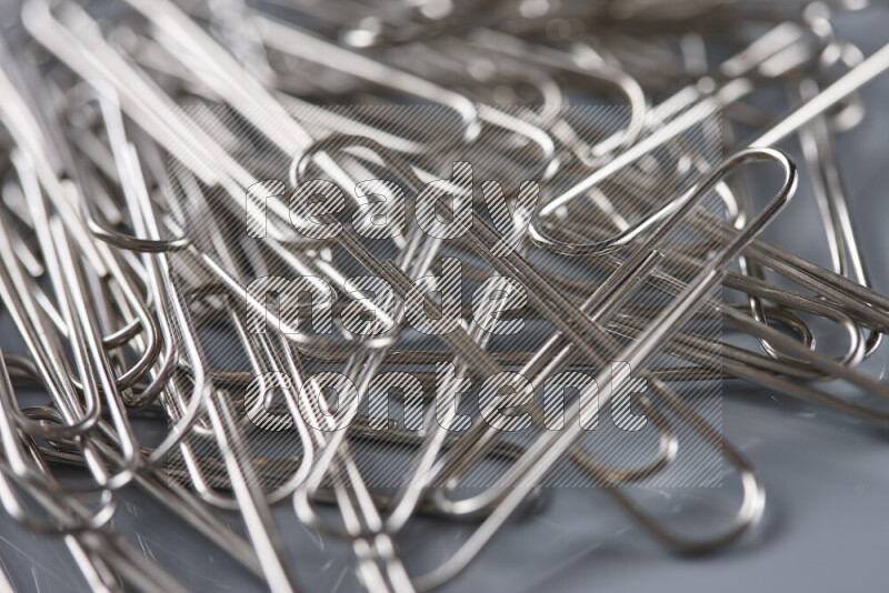 Silver paper clips isolated on a grey background