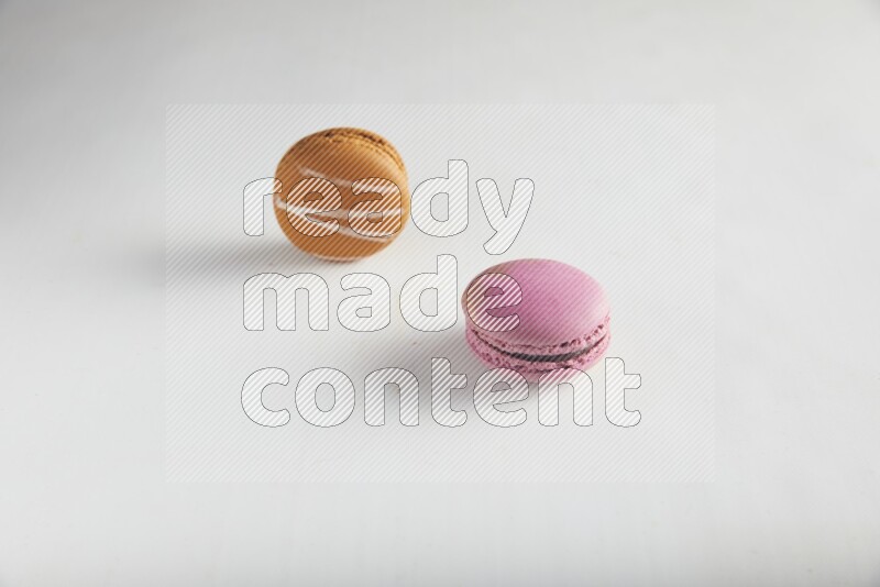 45º Shot of of two assorted Brown Irish Cream, and Purple Strawberry macarons on white background