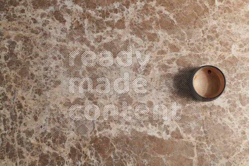 A multicolored pottery bowl on beige marble background