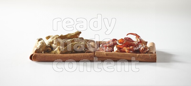 مربعان من أعواد القرفة ممتلئان بالفلفل الحار المجفف وأصابع الكركم علي خلفية بيضاء