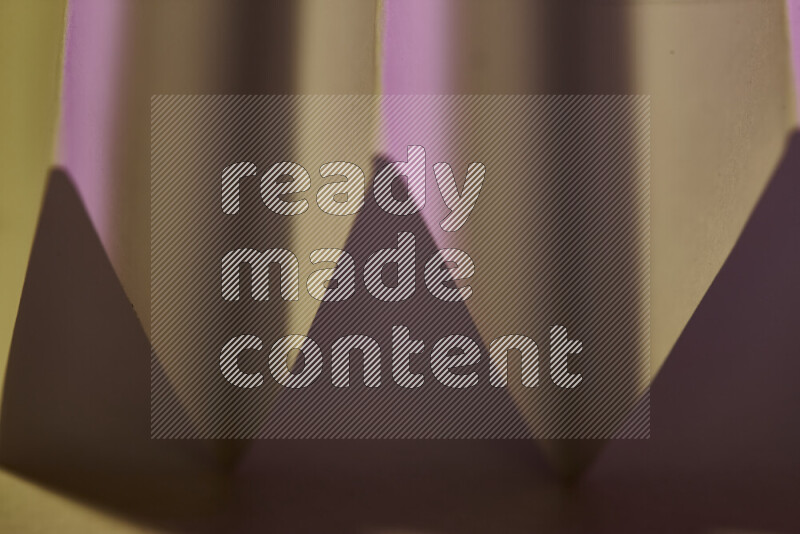 A close-up abstract image showing sharp geometric paper folds in pink gradients and warm tones