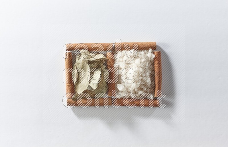 2 squares of cinnamon sticks full of white salt and laurel bay leaves on white flooring