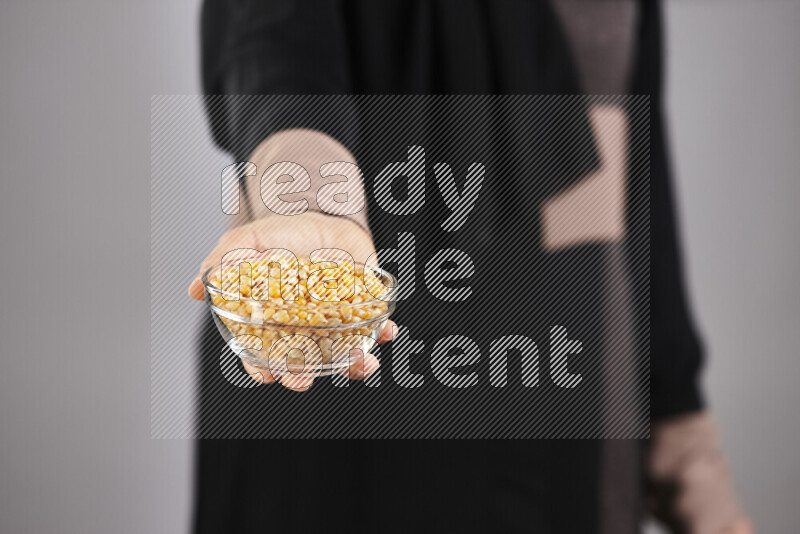 Woman in abaya holding different kinds of legumes in different positions