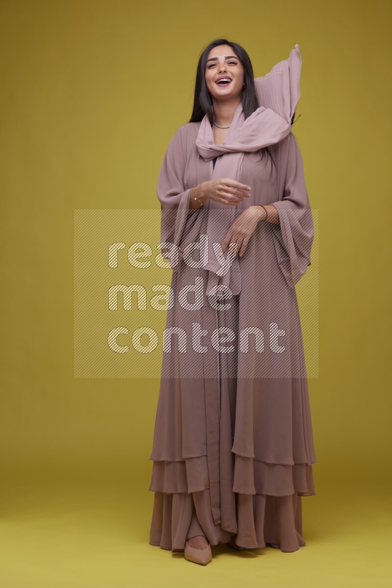 A woman Posing on a Yellow Background wearing Brown Abaya