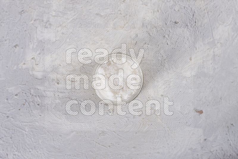 A glass jar full of coarse sea salt crystals on white background