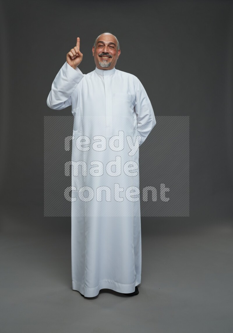 Saudi man without shomag Standing Interacting with the camera on gray background
