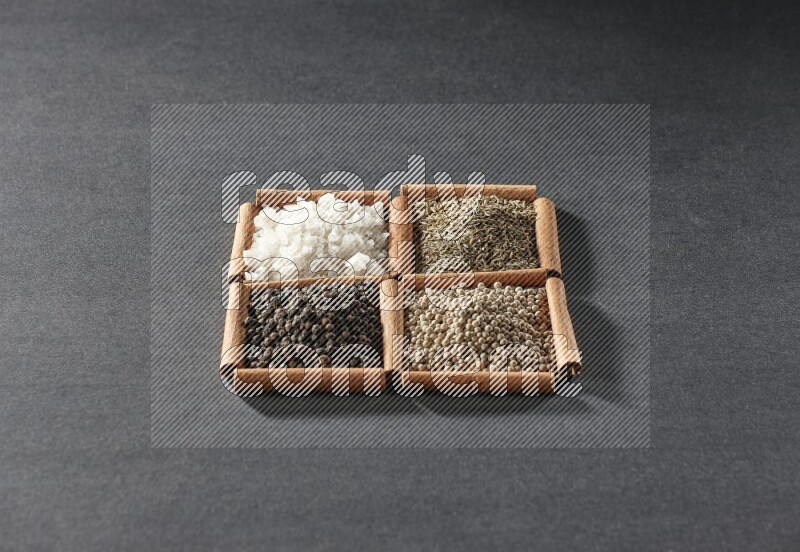 4 squares of cinnamon sticks full of black pepper, cumin, white pepper and white salt on black flooring