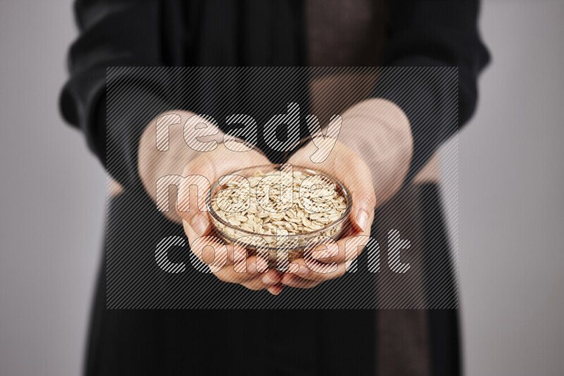 Woman in abaya holding different kinds of legumes in different positions