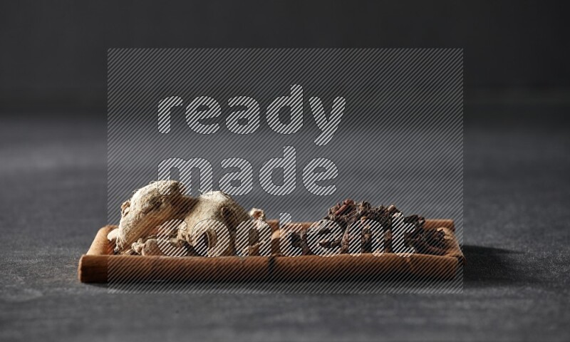 مربعان من أعواد القرفة ممتلئان بالقرنفل والزنجبيل المجفف علي خلفية سوداء