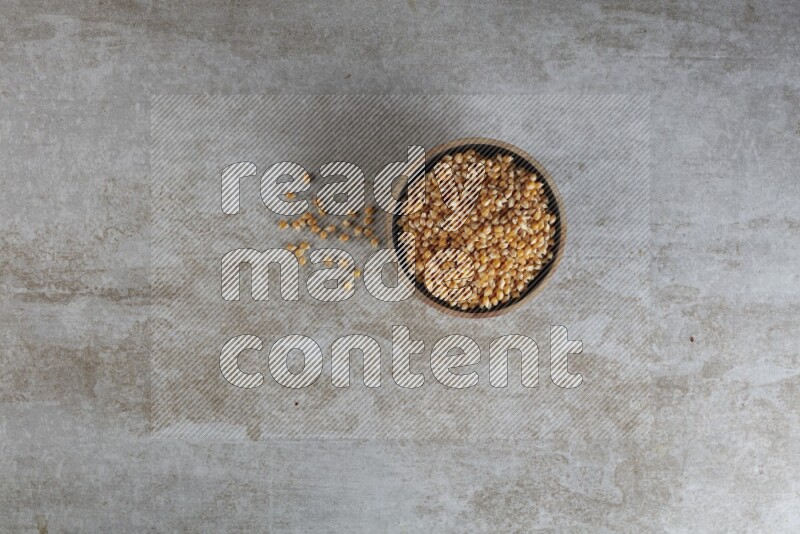 corn kernel in a wooden bowl on a grey textured countertop
