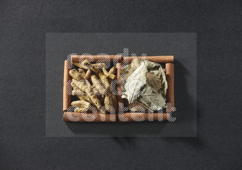 2 squares of cinnamon sticks full of bay laurel leaves and turmeric fingers on black flooring