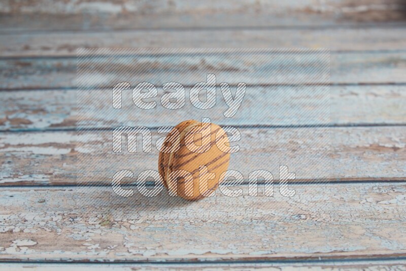 45º Shot of light brown Almond Cream macaron on light blue wooden background
