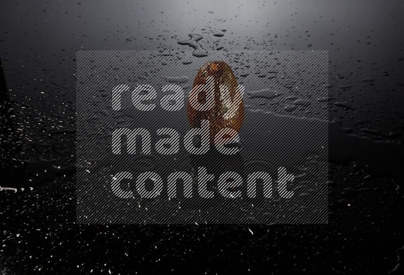 A whole avocado on black background with water drops.