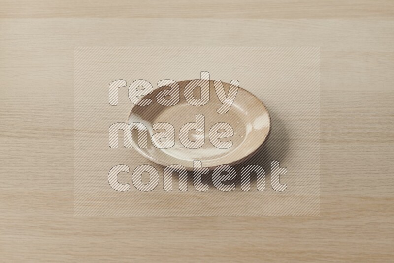 A beige pottery plate on light wooden background