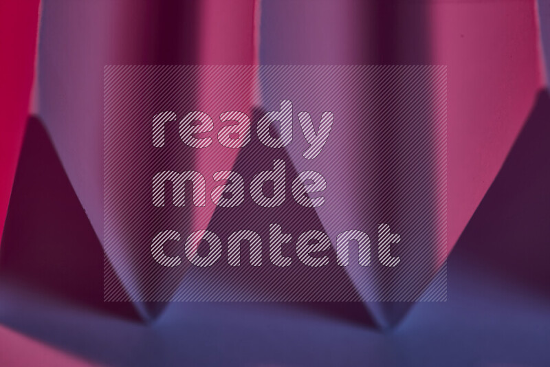 صورة مجردة مقربة تظهر طيات ورقية هندسية حادة بتدرجات اللون الارجواني