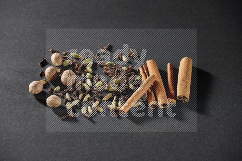 Cardamom, cloves, nutmeg and cinnamon sticks on black flooring