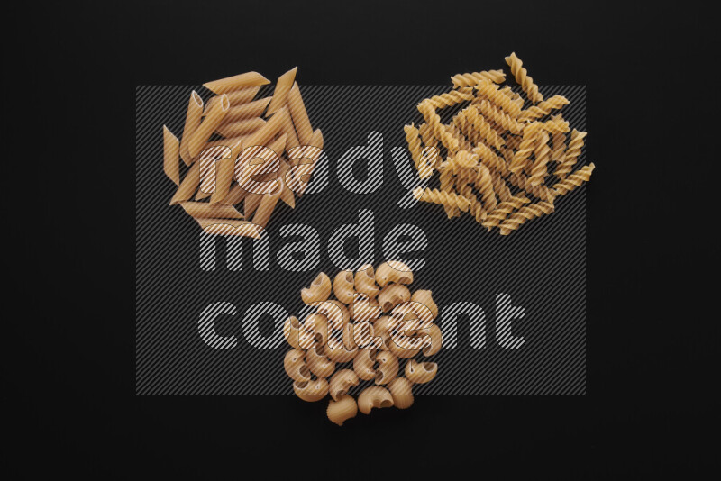 Different pasta types in bunches on black background