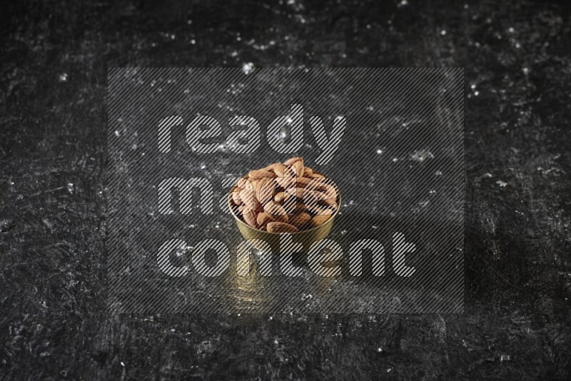 Nuts in a metal bowl in a dark setup