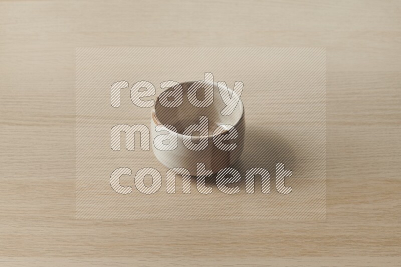 A beige pottery bowl on light wooden background