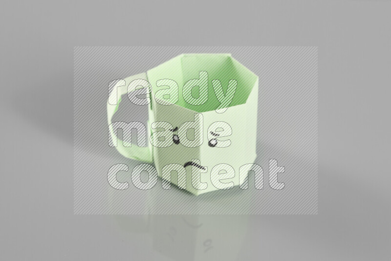 Origami cup on grey background