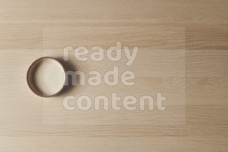 A beige pottery oven bowl on light wooden background