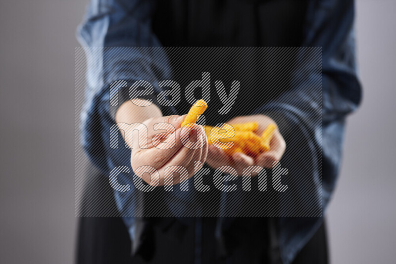 Woman in abaya holding different kinds of snacks in different positions
