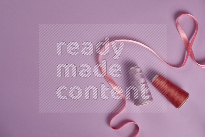 A pink and purple collection of sewing and tailoring tools arranged on a purple background
