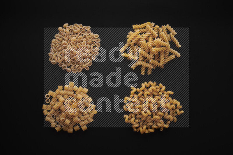 Different pasta types in bunches on black background