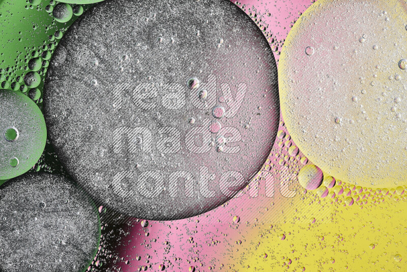Close-ups of abstract oil bubbles on water surface in shades of yellow, green and pink